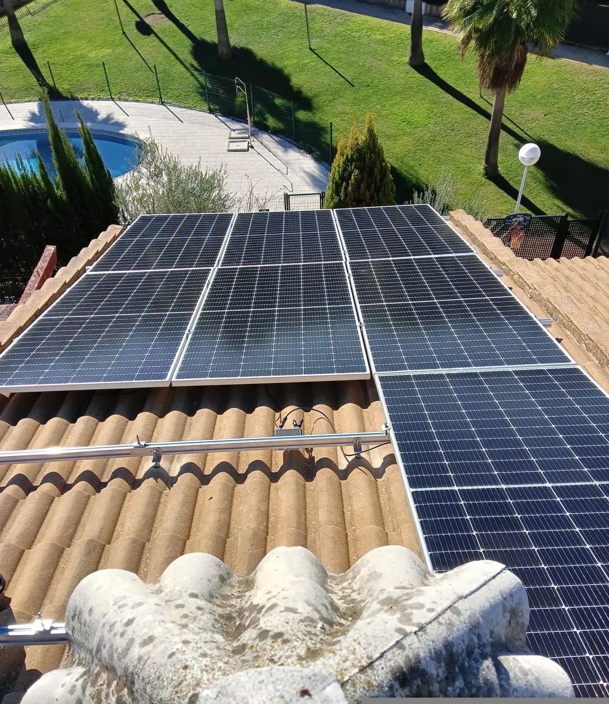 Paneles fotovoltaicos en tejado junto a un jardín