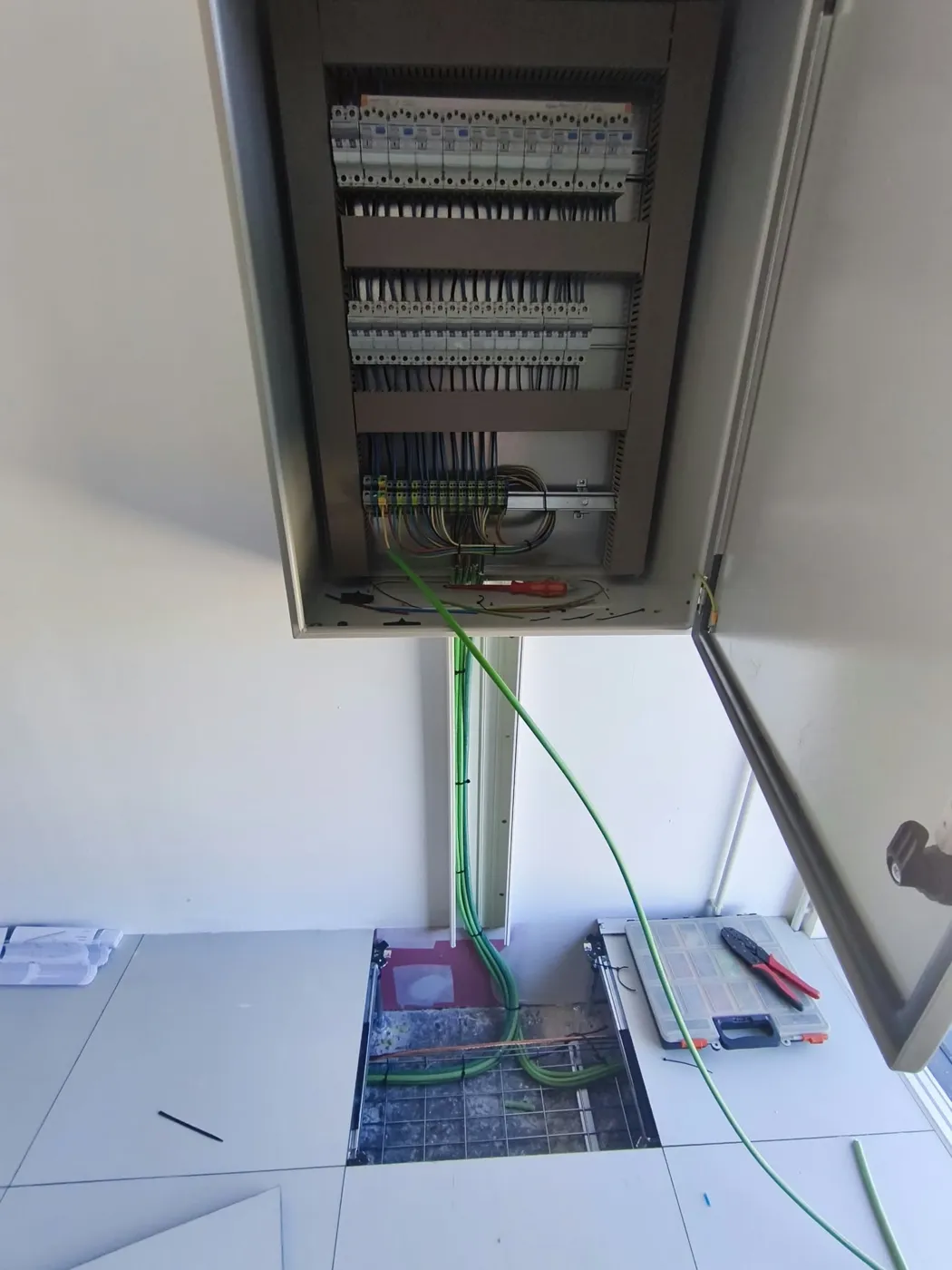 Cuadro eléctrico sobre suelo técnico con cables de tierra bajando por canaleta
